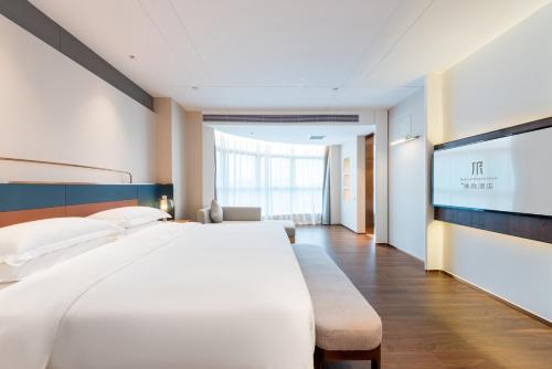 a hotel room with a large bed and a flat screen tv at Mehood Elegant Hotel Guangzhou Baiyun Airport Huadu Cultural Tourism City in Huadong