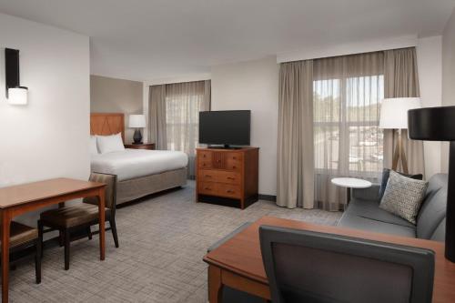 a hotel room with a bed and a couch and a tv at Residence Inn by Marriott Fayetteville Cross Creek in Fayetteville