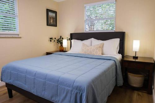 a bedroom with a bed with a blue comforter and two windows at House near Tampa Zoo and Busch Gardens, free high speed wifi in Tampa