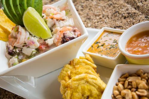 a plate of food with shrimp and dip and nuts at Hotel Solymar in Puerto Ayora