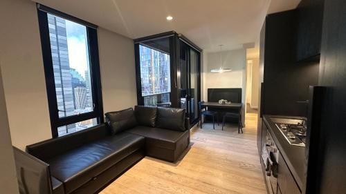 - un salon avec un canapé en cuir et une table dans l'établissement Nest Apartments MEET Empire, à Melbourne