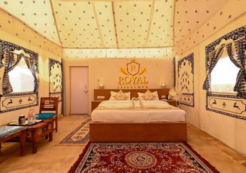 a bedroom with a bed and a table and windows at Royal Empire Resort Jaisalmer in Jaisalmer