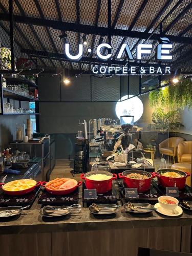 a counter with several dishes of food in a restaurant at U Sabai Hotel Bangkok in Bangkok