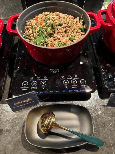 a pot of food on a stove with a spoon at U Sabai Hotel Bangkok in Bangkok
