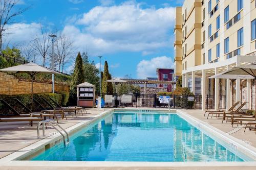 a swimming pool with chairs and umbrellas next to a building at Fairfield Inn & Suites by Marriott Atlanta Lithia Springs in Lithia Springs