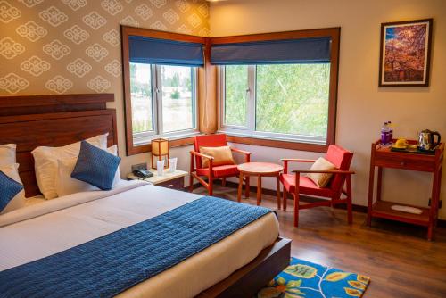 a bedroom with a bed and chairs and a desk at ANGKASA LADAKH RESORT in Leh