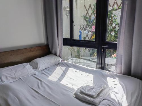 an unmade bed in a room with a window at Shanghai Garden Apartment - Near Downtown Wukang Road in Shanghai