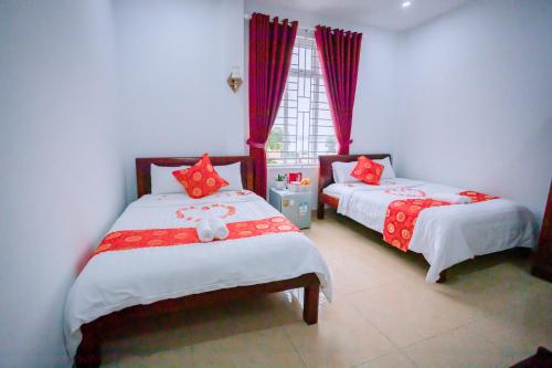 1 dormitorio con 2 camas con almohadas rojas y ventana en OPA HOTEL HUE en Thôn Lại Thê