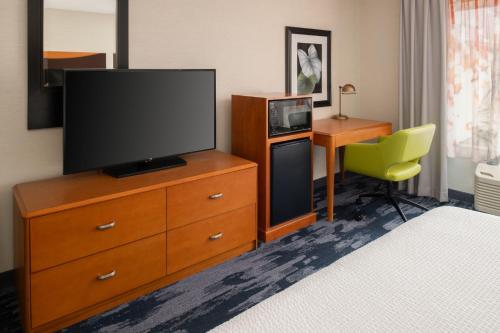 a room with a television on a dresser with a desk at Fairfield Inn & Suites by Marriott Portland Airport in Portland