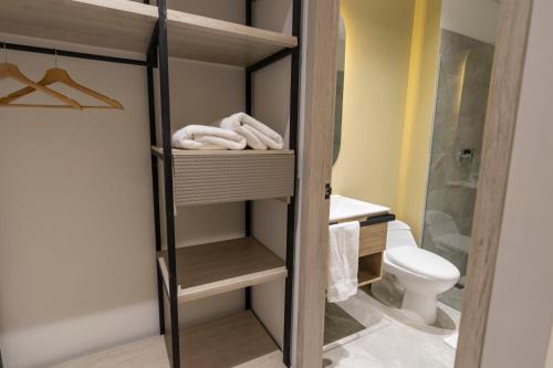 a bathroom with a shower and a toilet and towels at Sonata 44 Hotel Laureles in Medellín