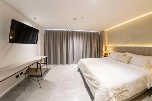 a bedroom with a bed and a desk and a television at Sonata 44 Hotel Laureles in Medellín