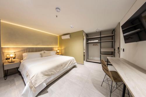 a bedroom with a large bed and a desk at Sonata 44 Hotel Laureles in Medellín