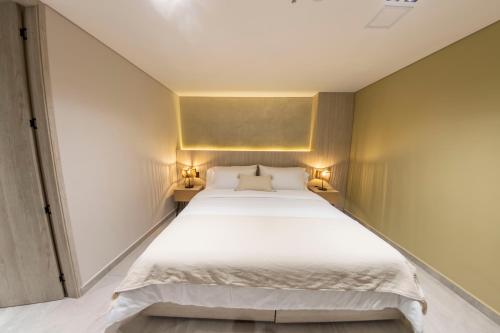 a bedroom with a large white bed with two lamps at Sonata 44 Hotel Laureles in Medellín