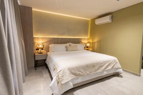 a bedroom with a large white bed and two lamps at Sonata 44 Hotel Laureles in Medellín