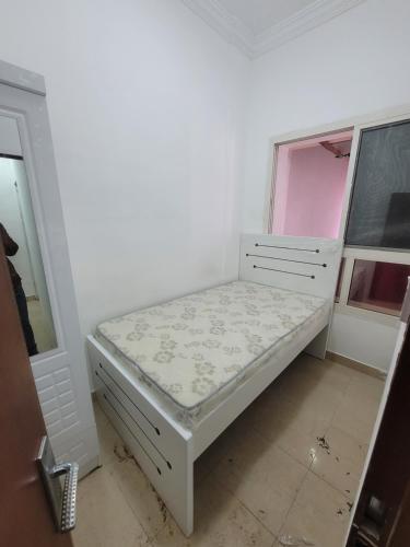 Cama blanca pequeña en habitación con ventana en Punjab Guest House en Dubái