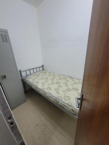 Cama pequeña en habitación con puerta en Punjab Guest House en Dubái