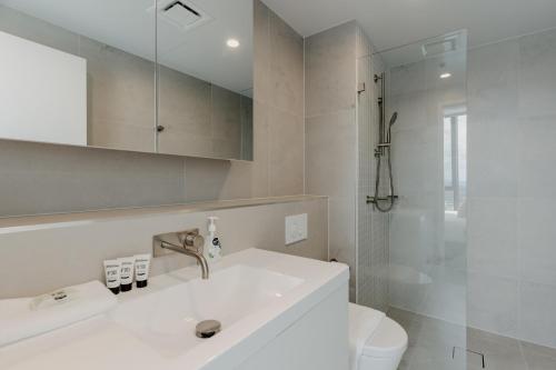 a white bathroom with a sink and a toilet at Panoramic Lake View 2-Bed with Pool, Gym and BBQ in Belconnen