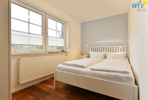 a white bed in a room with a window at Luv und Lee - Ferienwohnung Juister Stuv in Juist