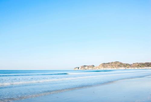 a beach with blue water and rocks in the background at THE VIEW KAMAKURA in Kamakura