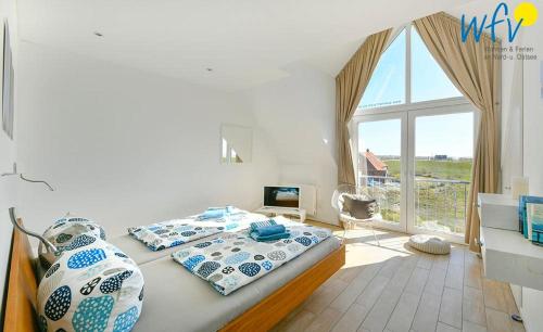 a bedroom with two beds and a large window at Haus Kiek in't Watt- Ferienwohnung Quartier 7 Ost in Juist