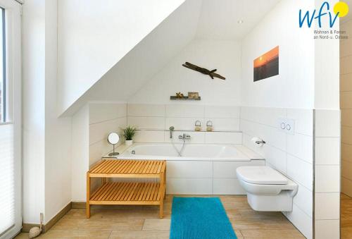 a white bathroom with a tub and a toilet at Haus Kiek in't Watt- Ferienwohnung Quartier 7 Ost in Juist