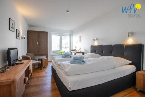 a bedroom with a large bed and a television at Appartement-Haus Regina Ferienwohnung Sonnendeck in Borkum