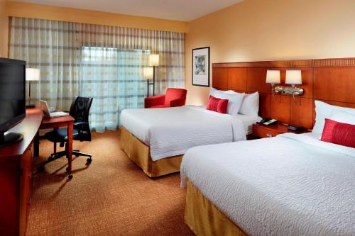 a hotel room with two beds and a desk and a television at Courtyard Birmingham Hoover in Hoover