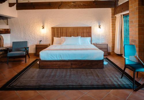 a bedroom with a bed and two chairs and a desk at BOTANIQ HOTEL BOUTIQUE in Valle de Bravo