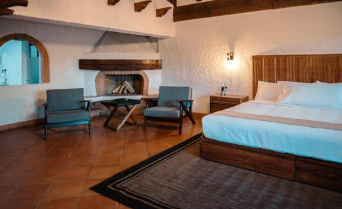 a bedroom with a bed and a table and a fireplace at BOTANIQ HOTEL BOUTIQUE in Valle de Bravo