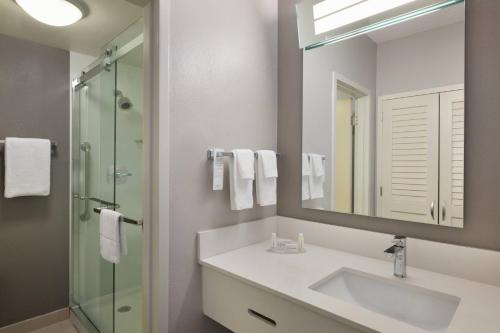 y baño con lavabo, espejo y ducha. en Courtyard Fort Myers Cape Coral, en Fort Myers