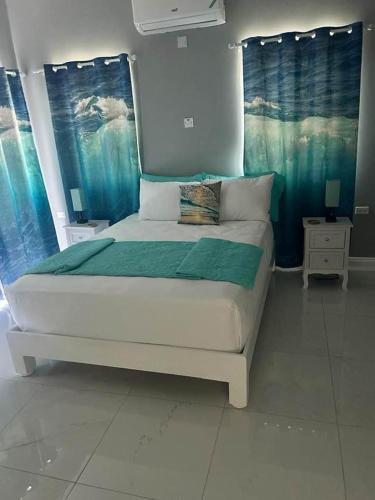 a bedroom with a large bed with blue curtains at CLIFF POINT in Treasure Beach