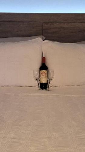 a bottle of wine sitting on a bed with two glasses at Trujillo Alto Quiet and Cozy, Fully Equipped and Pet-Friendly in Trujillo Alto