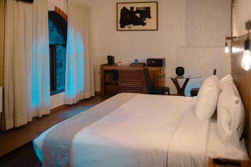 a bedroom with a large white bed and a desk at BOTANIQ HOTEL BOUTIQUE in Valle de Bravo