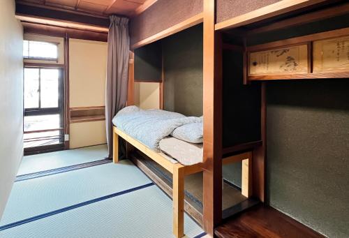a room with two bunk beds and a window at Hostel Murasaki Ryokan Miyagawa in Takayama