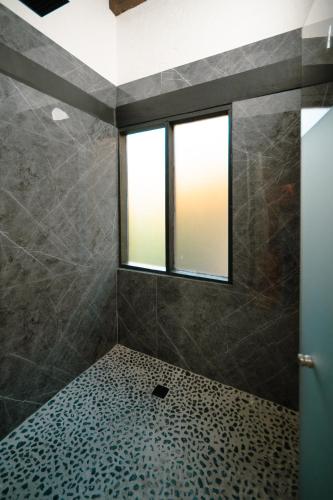 a bathroom with a shower with a window at BOTANIQ HOTEL BOUTIQUE in Valle de Bravo