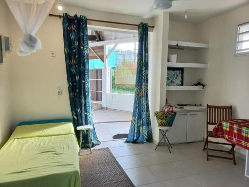 um quarto com uma cama com cortinas azuis e uma cozinha em ChezLou1 em Fort-de-France