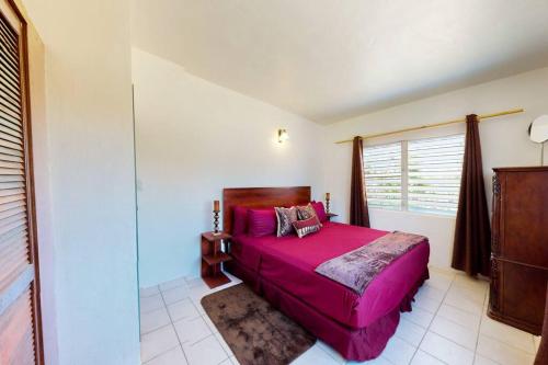 sypialnia z różowym łóżkiem i oknem w obiekcie South Hill Cottage w mieście Sandy Ground Village