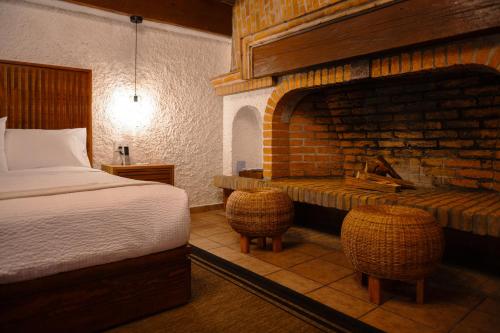 a bedroom with a bed and a brick fireplace at BOTANIQ HOTEL BOUTIQUE in Valle de Bravo