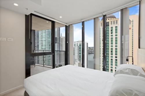 um quarto com uma grande cama branca e janelas grandes em Cosy 1-Bed with River Views Pool Gym & BBQ em Brisbane