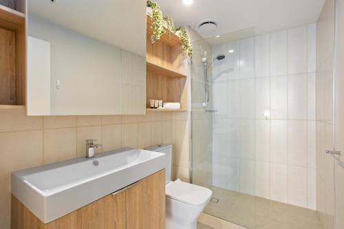 uma casa de banho com um lavatório branco e um WC. em Cosy 1-Bed with River Views Pool Gym & BBQ em Brisbane