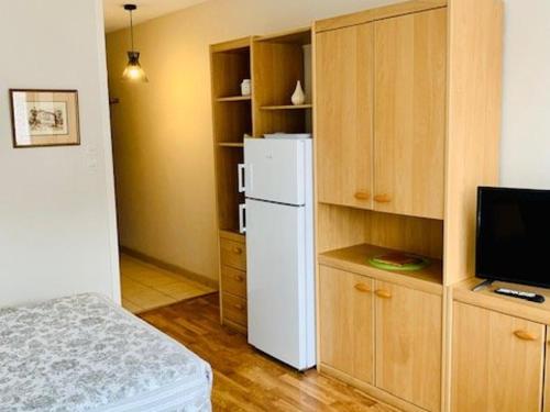 Il comprend une cuisine équipée d'un réfrigérateur blanc et une télévision. dans l'établissement Studio cosy avec loggia - 2 pers. - Centre-ville et cures à proximité, animaux acceptés - FR-1-703-172, à Amélie-les-Bains-Palalda