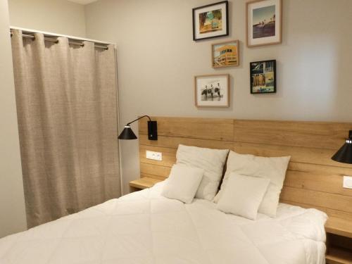 a bedroom with a white bed with a wooden headboard at Appartement 2 ch, accès plage direct, rez-de-jardin, piscine, animaux OK - FR-1-194-284 in La Tranche-sur-Mer