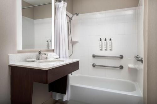 a bathroom with a sink and a tub and a shower at SpringHill Suites Dallas Addison/Quorum Drive in Dallas