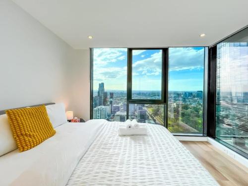 a white bed in a room with large windows at Pride CBD Skyline View 2B2B Apartment LV32 in Melbourne
