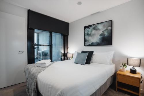 Un dormitorio con una gran cama blanca y una ventana en Center 2-Bed with Gym, Sauna, Indoor Pool & Views, en Canberra