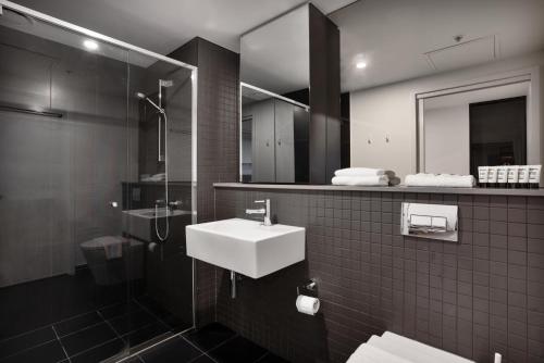 y baño con lavabo y espejo. en Center 2-Bed with Gym, Sauna, Indoor Pool & Views, en Canberra