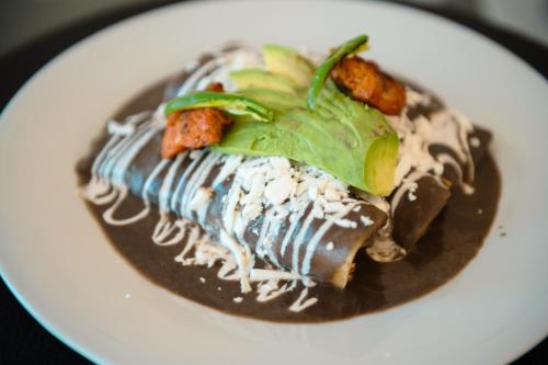 a plate of food with chocolate sauce and vegetables at BOTANIQ HOTEL BOUTIQUE in Valle de Bravo