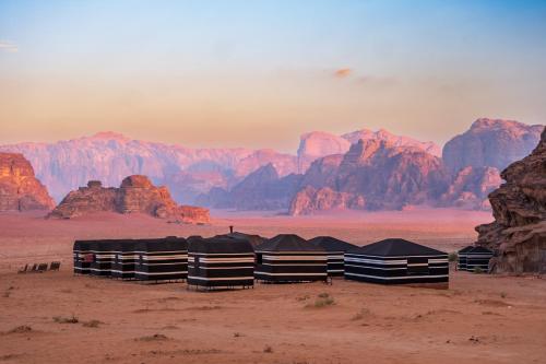 a group of tents in the desert with mountains at Wadi Rum Fire Camp in Wadi Rum