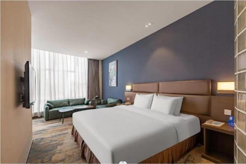 a bedroom with a large white bed and a couch at Holiday Inn Express Shenyang North Station by IHG in Shenyang
