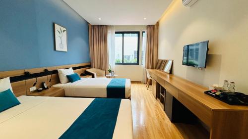 um quarto de hotel com duas camas e uma televisão de ecrã plano em Mango Hotel - Ha Noi Railway station em Hanói